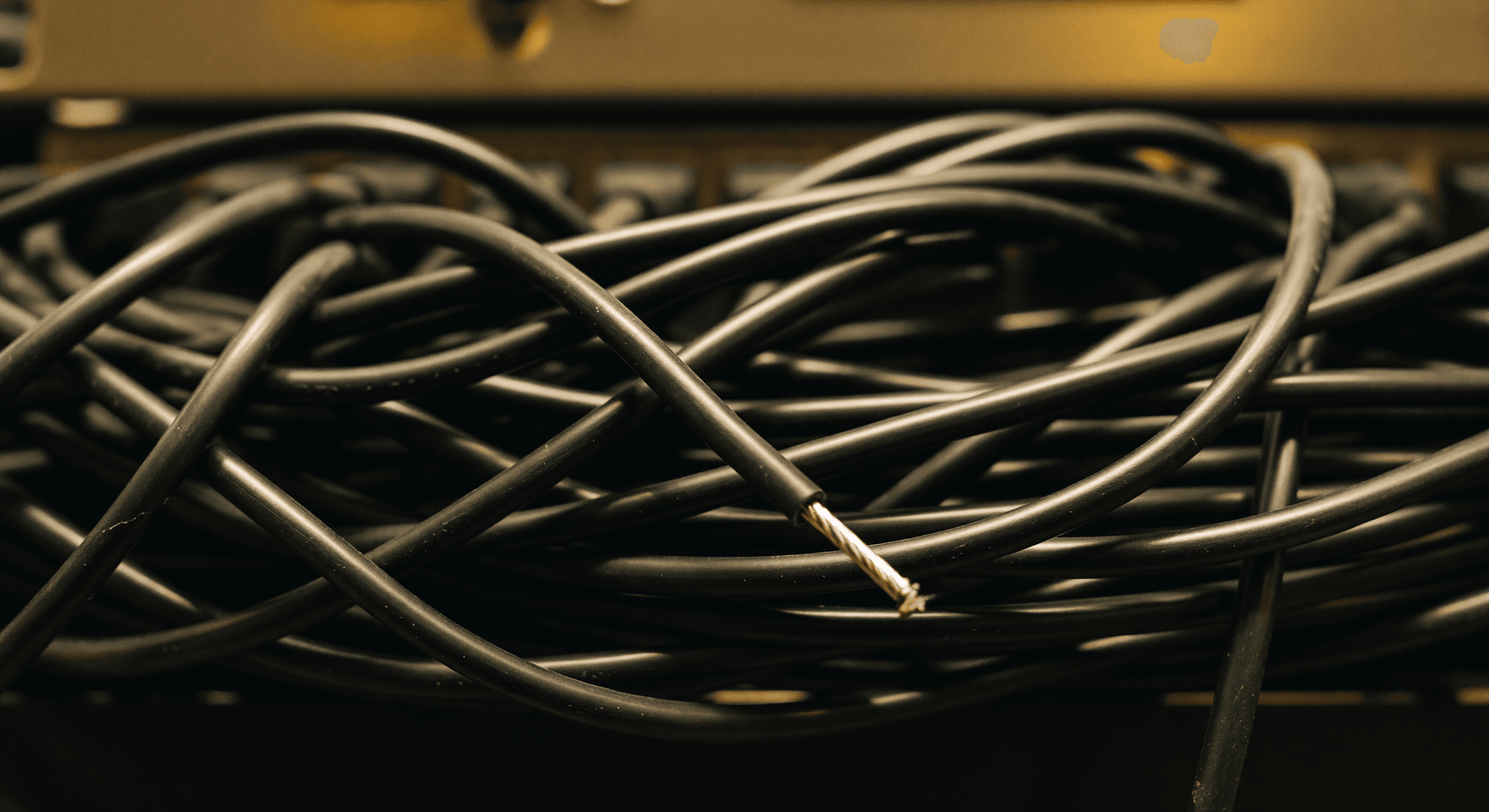 Extreme macro close-up of tangled patch cables in a small-office network rack, with a single loose strand pulled forward.